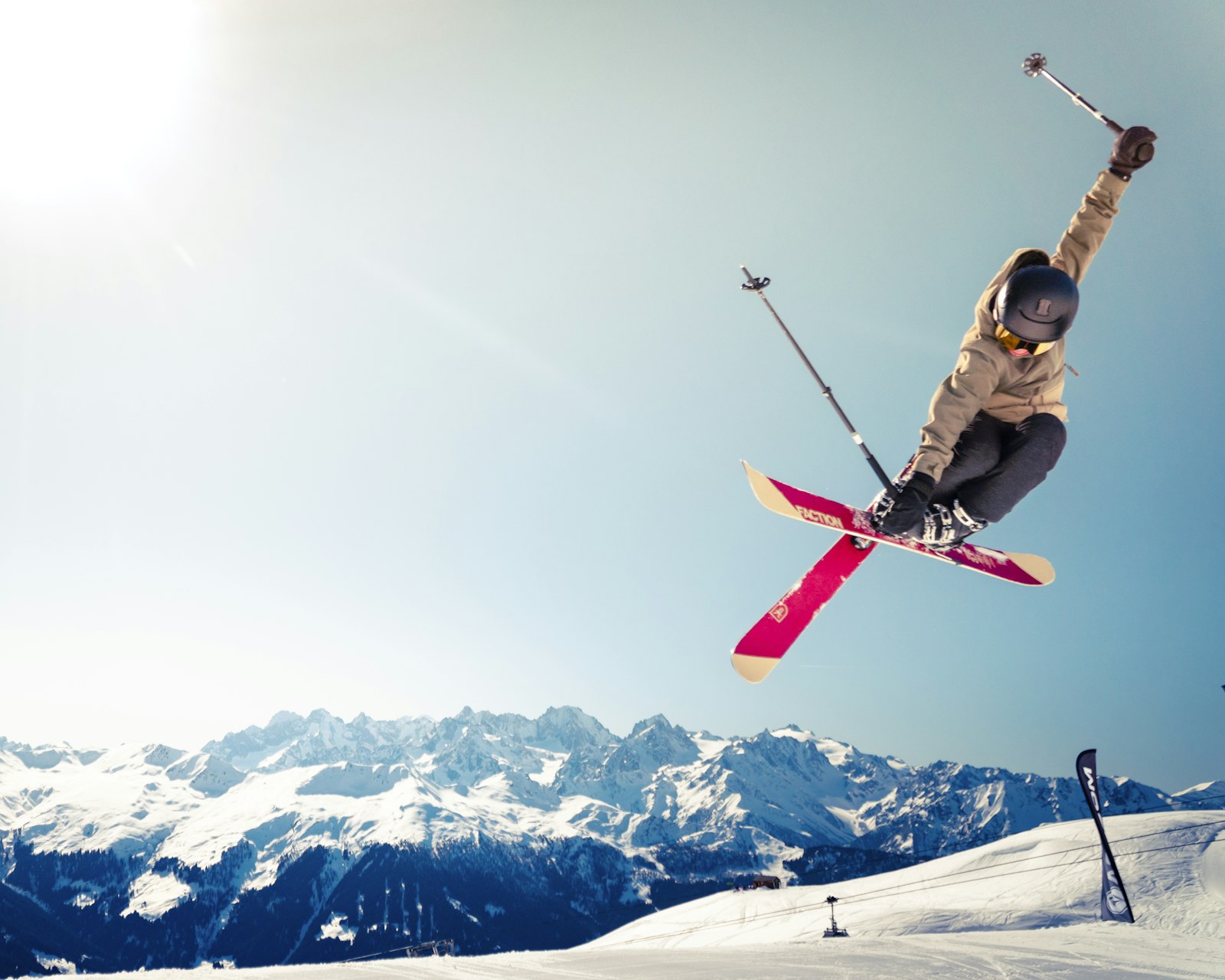 Freestyle skier in mid-air above snowy peaks