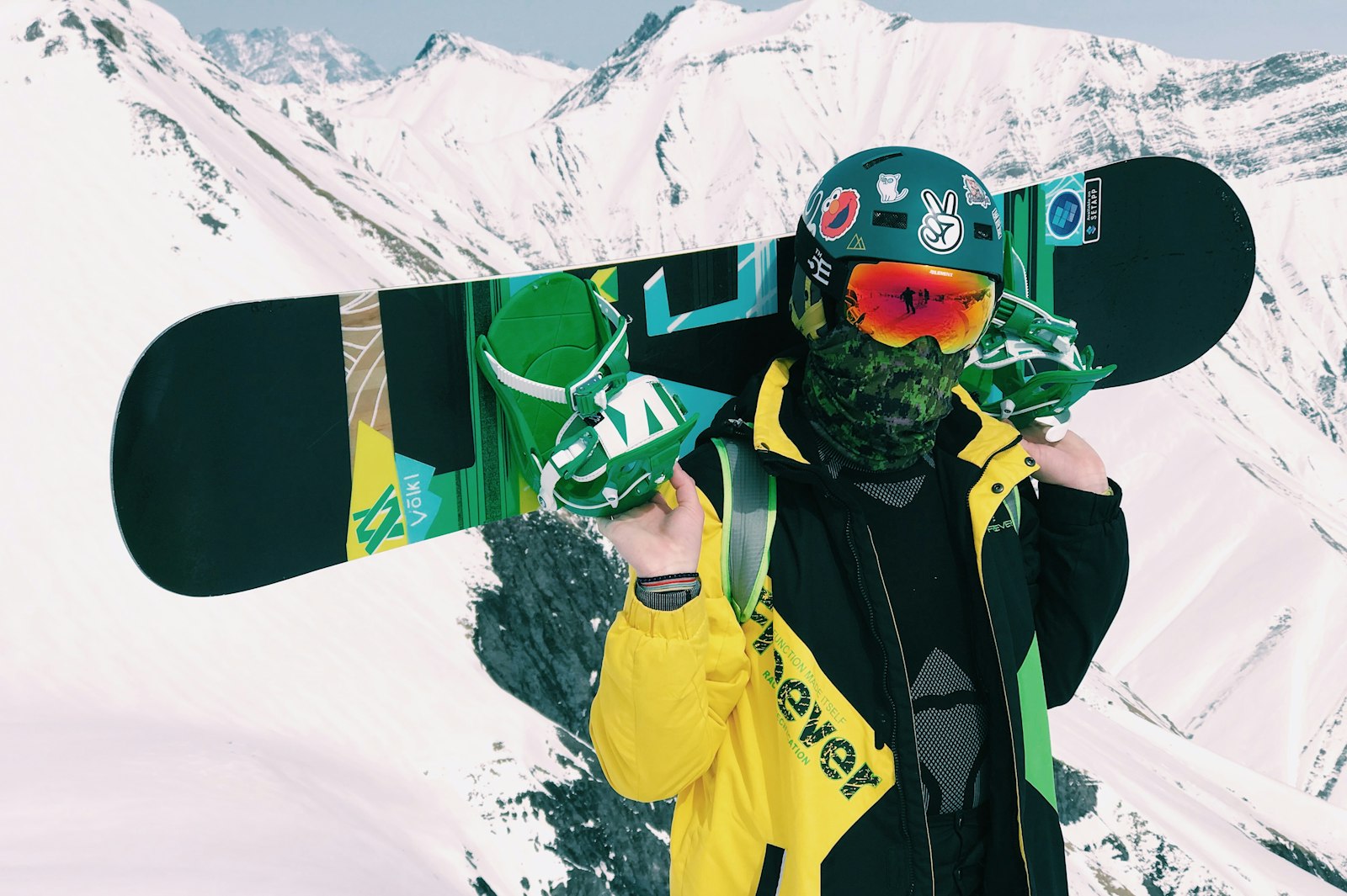 Snowboarder holding a board in front of snowy mountains